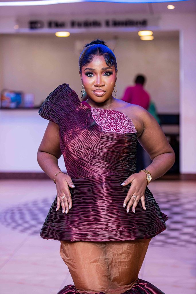 A guest in a pleated plum gown poses on the red carpet at the 2026 Africa Magic Viewers' Choice Awards