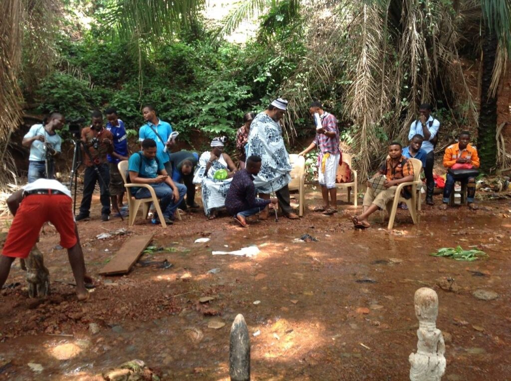 A Nollywood film crew and actors on location in a forest clearing