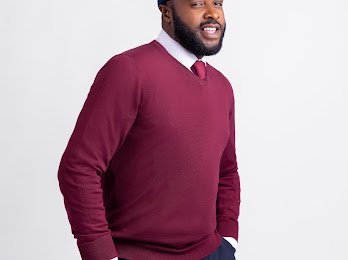 Femi Adebayo in a maroon jumper and tie