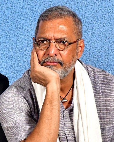 Nana Patekar resting his chin on his hand, wearing glasses and a white scarf