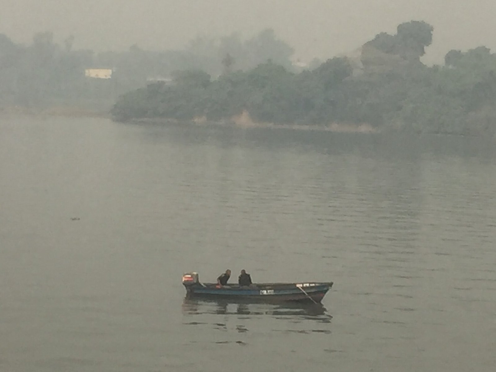 A small canoe with passengers on the Lagos Lagoon on a hazy day