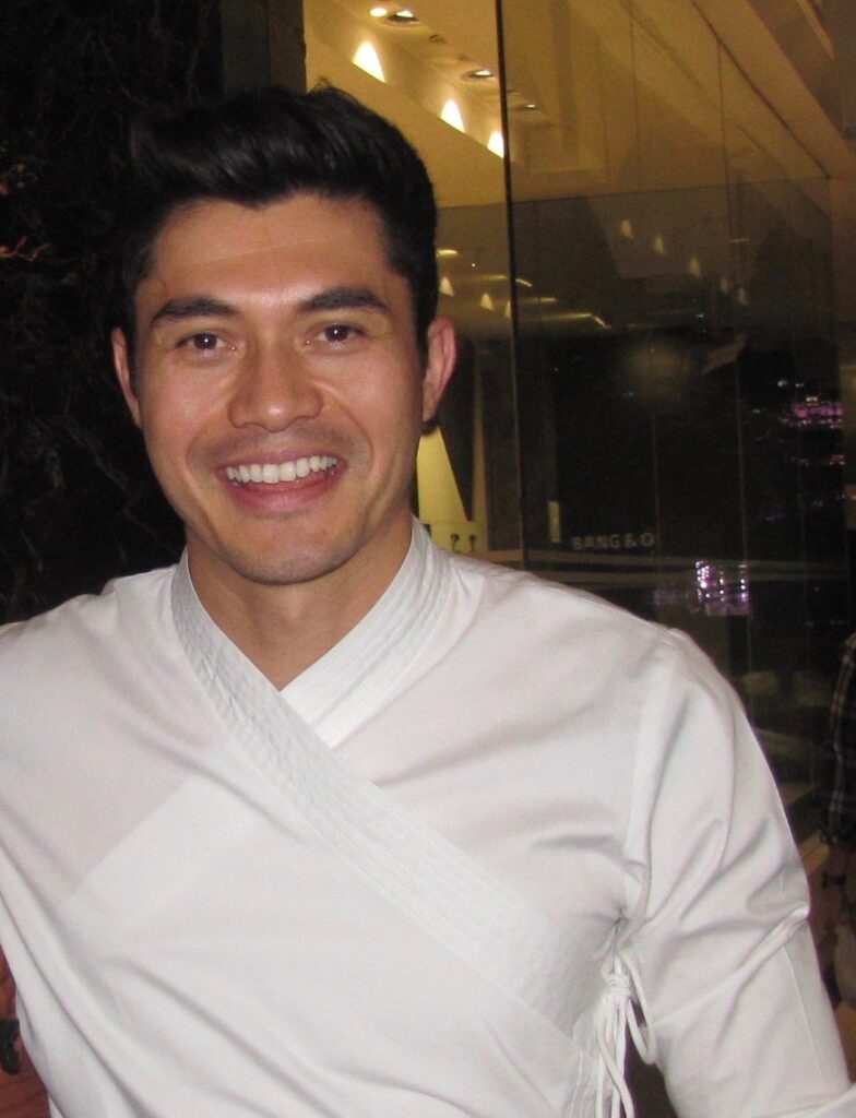 Henry Golding smiling at a wrap event for Crazy Rich Asians
